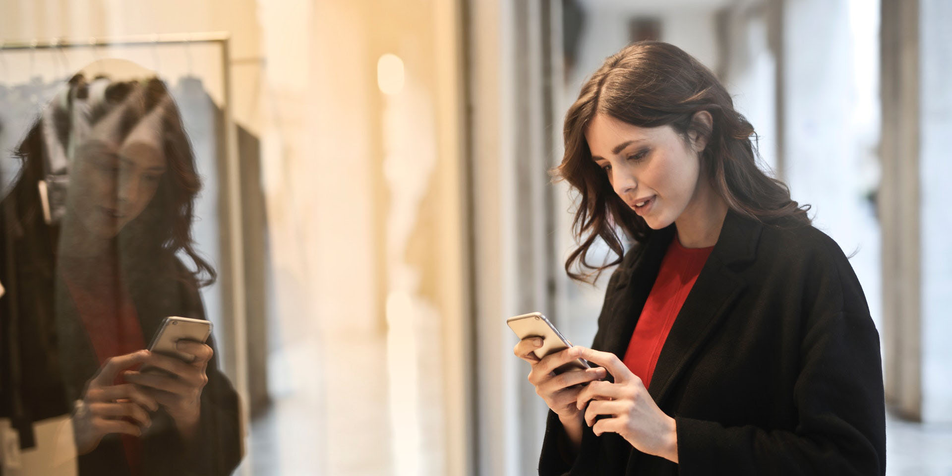 Customer window shopping using her phone, interested in product assortment and fashion retail